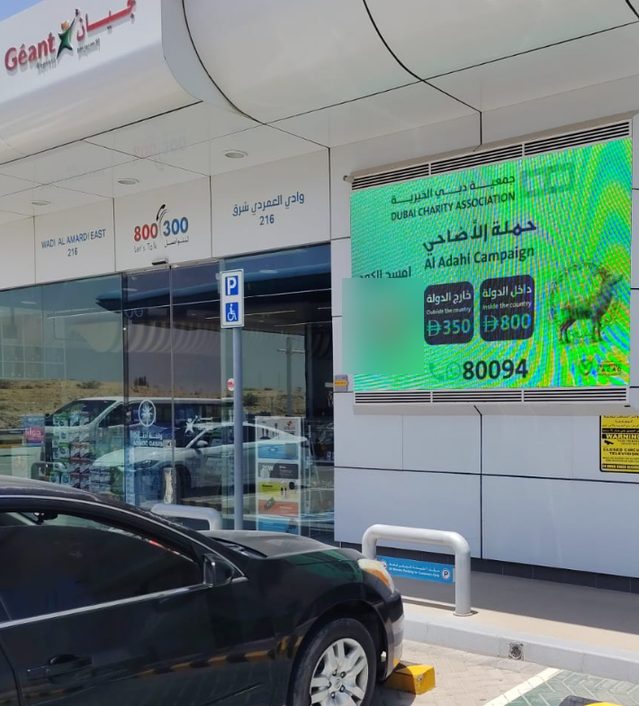 شاشة جمعية دبي الخيرية على واجهة متجر في محطة وقود