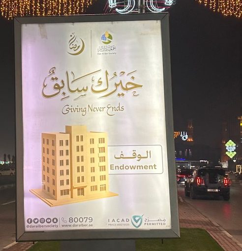 لوحة مضاءة لجمعية دار البر عن الوقف بجانب طريق ليلا