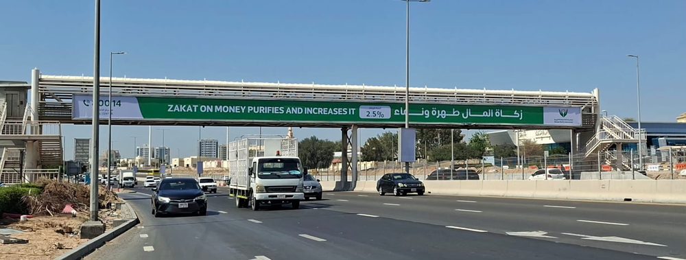 لافتة جمعية الشارقة الخيرية على جسر مشاة فوق طريق بعدة مسارات