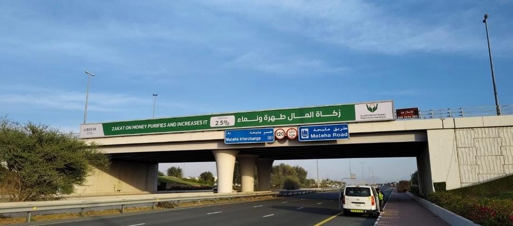 لافتة جمعية الشارقة الخيرية على جسر فوق طريق سريع من زاوية أخرى
